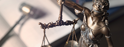 Justice with her scales, and a gavel and book in the background