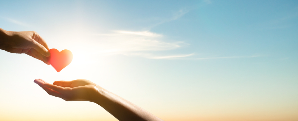 Image of a person handing a heart to another person.